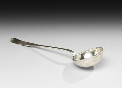 une cuillère en argent posée sur une surface blanche
