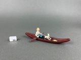 a miniature figurine of a man and a dog in a boat