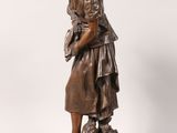 an antique bronze statue of a woman holding a basket