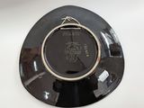 a black plate with a gold rim on a white table