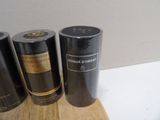 three black bottles of perfume sitting on a wooden cutting board