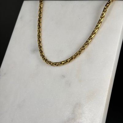 a close up of a gold chain on a marble block