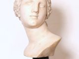 marble bust of a woman with curly hair on a marble pedestal