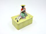 a figurine of a woman sitting on top of a stack of books