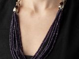the woman is wearing a necklace with purple beads and a black shirt