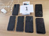 Plusieurs téléphones portables sont posés sur une table, à côté d'un chargeur branché.