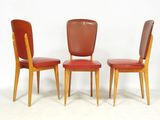 trois fauteuils en cuir rouge aux pieds en bois, adossés à un mur blanc