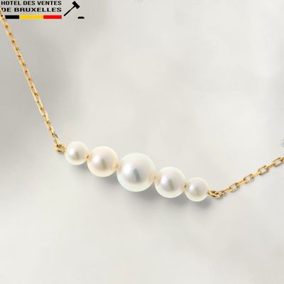 un collier de perles blanches avec une chaîne en or sur fond blanc