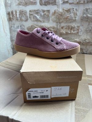 purple shoes on top of a cardboard box in front of a brick wall
