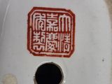 a white porcelain vase with a red design on it
