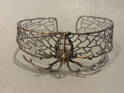 a close up of a metal bracelet with a butterfly on it