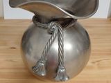 a silver vase with a rope wrapped around it on a wooden table