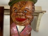 a wooden statue of a man with a hat on a shelf