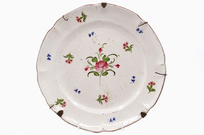 EST Assiette en faïence émaillée polychrome à décor floral.