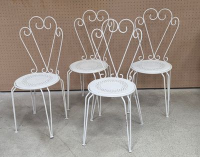 three white metal chairs sitting next to each other in front of a wall