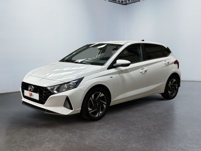La voiture blanche est garée dans une pièce blanche au sol noir.