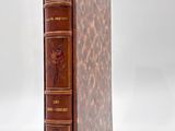 an old book with a brown leather cover sitting on top of a white surface