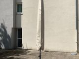 un grand parapluie fixé à un mât devant un immeuble