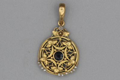 un pendentif en or orné d'une pierre noire entourée de perles