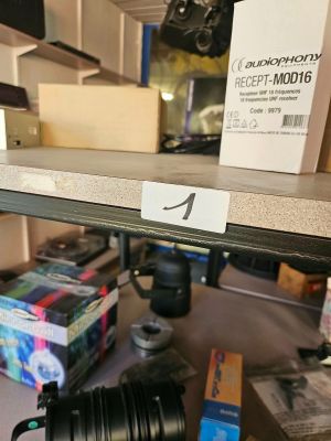 un appareil photo posé sur une étagère dans une pièce où se trouvent de nombreux cartons