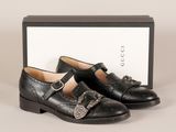 une paire de chaussures en cuir noir à boucles et une boîte