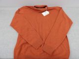 un pull orange posé sur un canapé blanc