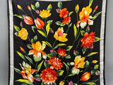 une photo d'une écharpe à motifs floraux noirs et orange suspendue à une corde à linge