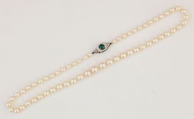 un collier de perles blanches muni d'un fermoir en émeraude et diamants