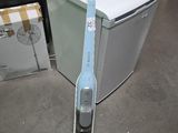 un aspirateur posé par terre devant un réfrigérateur