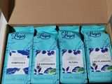 four bags of coffee sit in a cardboard box on a table