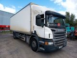 un camion blanc garé sur un parking, avec d'autres camions en arrière-plan