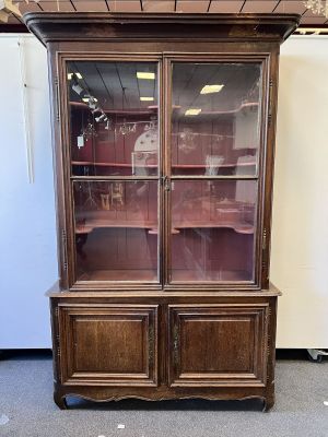 un vieux vaisselier en bois avec des portes vitrées, dans une pièce