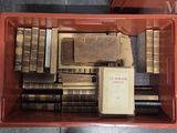 une boîte rouge remplie de vieux livres, posée par terre