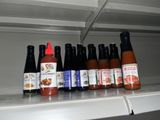 many bottles of hot sauce on a shelf in a refrigerator