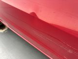 a close up of a red car parked in a parking lot
