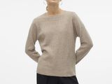 a woman in a beige sweater and black pants stands with her hands on her hips