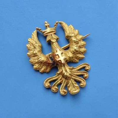 une image représentant une broche en forme d'oiseau doré sur fond bleu