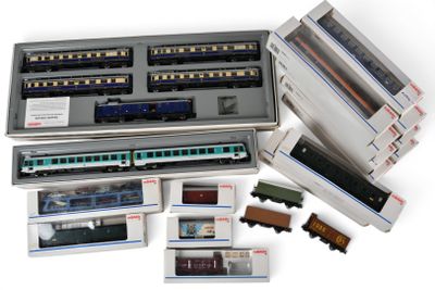 de nombreux petits trains miniatures dans une boîte posée sur une surface blanche