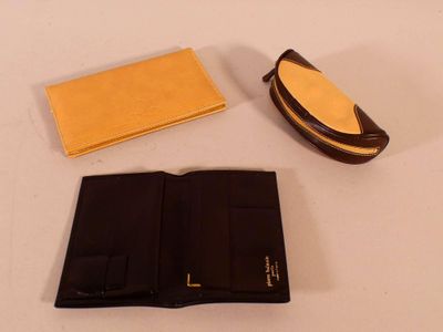 un portefeuille, un étui à portefeuille et une paire de lunettes posés sur une table