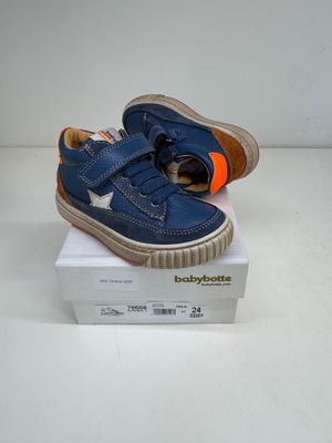 des chaussures de petit garçon bleues et orange posées sur une boîte blanche