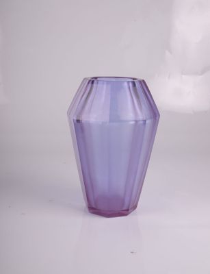 vase en verre violet posé sur une surface blanche, avec des nuages en arrière-plan