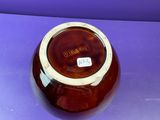 brown and white bowl sitting on a purple surface with a tag on it