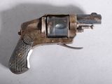 un petit pistolet posé sur une surface blanche