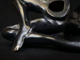 a silver statue of a frog sitting on a black surface