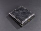 an old black box sitting on top of a table next to a black surface