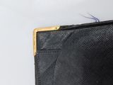 someone is holding a black purse with a gold metal clasp