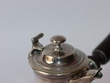 a silver tea pot with a black handle on a table