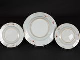 three white plates with gold rims are sitting on a black surface