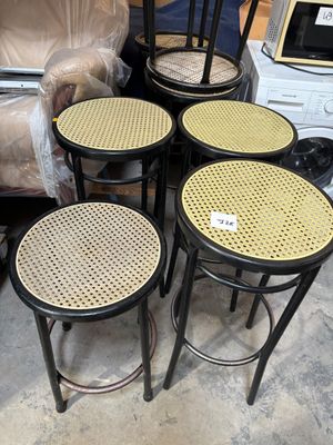 four stools and a table in a room with a couch in the background