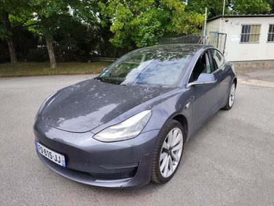 the tesla model 3 is parked in a parking lot in front of a house
